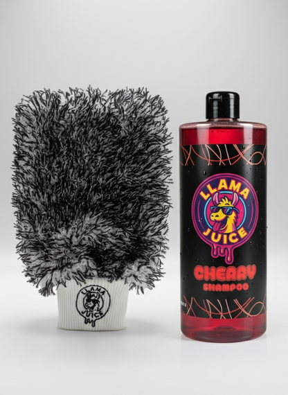 Black and gray grooming brush next to a bottle of 'Llama Juice Cherry Shampoo' on a white background